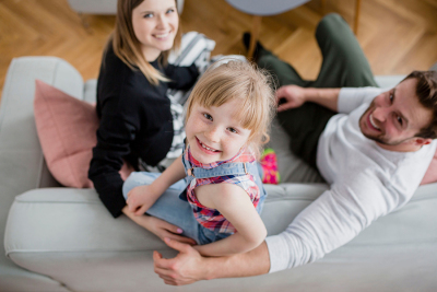 Glückliche Familie mit Eltern und Mädchen auf der Couch