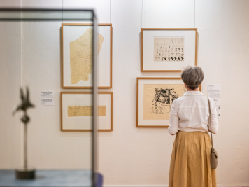Eine Frau steht im Ausstellungsraum und schaut sich Arbeiten von Gerhard Altenbourg an