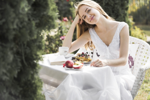 Eine lachende blonde jungen frau die an einem Tisch im Garten sitzt